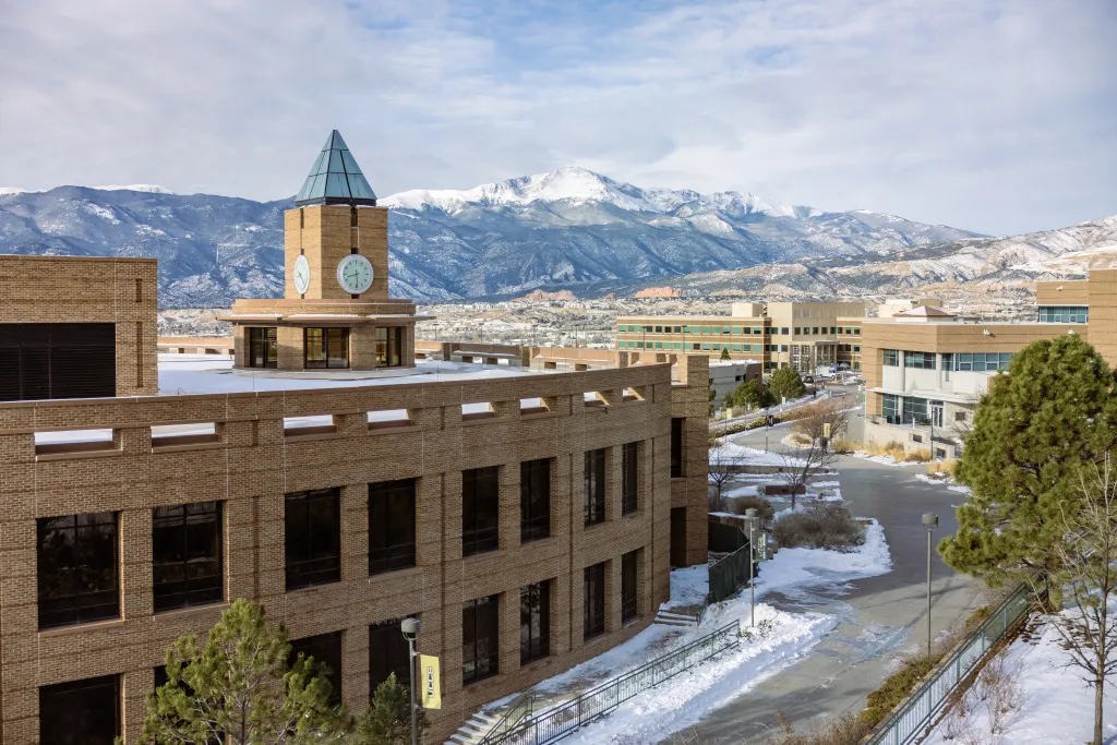 Snow-covered campus with El Pomar Clock Tower and Pikes Peak in the background